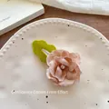 Détail d'une barrette à fleurs en tissu avec strass et feuille verte sur plateau - Barrette Fleur Rose Clair