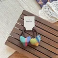 Details von farbenfrohen Herz-Haargummis mit Karomuster auf Holz- und Stoffhintergrund - Herz Scrunchie