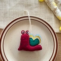 Cute snail-shaped plush keychain in dark red with colorful heart patterns and a white lanyard - Heart Snail