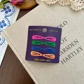 Lot de 8 barrettes à cheveux en métal mat coloré présentées sur un vieux livre rustique - Coloré