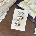 Detalle de lindas pinzas para el cabello de oso bordado con lazos marrones en fondo de madera - Clip de Oso Blanco Crema