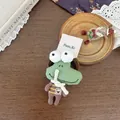 Gros plan d'un chouchou grenouille tricoté vert avec un haut rayé sur bois vintage - Style Grenouille Verte