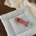 Detailed macro shot of a pink fish-shaped fabric brooch with wooden button eye on blue cushion - Pink Fish Button (NK1352)