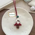 Dettaglio di un ciondolo natalizio in tessuto fatto a mano su un piatto di ceramica - Collana Albero di Natale Rosso
