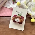 Detailed view of handmade fabric red apple hair clip with cute embroidered girl face on card - Red Apple Hair Clip