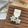 Dettagli elastici per capelli con stelle a quadri verdi su vassoio in legno stile rustico - Elastico per Capelli Stella Verde