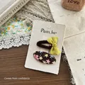Dettaglio di fermaglio per capelli con fiocco in tessuto e set di clip a fiori - Stile Floreale Ovale E Fiocco