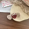 Détail de barrettes fraises tricotées à la main avec nœud sur assiette rustique - Barrette Fraise Rouge