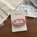 Nahaufnahme der rosa Lammwolle-Haarklammer mit handgefertigtem Etikett auf der Karte - Rosa Plüsch-Haarclip mit Buchstaben