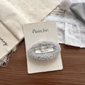 Detailansicht einer grauen Plüsch-Haarklammer mit handgemachtem Etikett - Grauer Plüsch-Haarclip mit Buchstaben