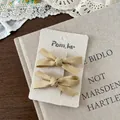 Detailansicht cremegelber Haarschleifen auf Markenkarte mit nostalgischem Vintage-Stil - Satin-Schleifen-Haarclip