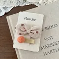Detail von beige gepunkteter Schleifen-Haarklammer und orangefarbenem Filzball - Schleife Punktmuster Haarspange
