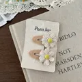 Detail von Häkel-Gänseblümchen-Haarspangen mit Spitzenblättern auf Cremekarte - Blumen Design