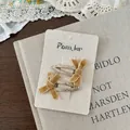 Nahaufnahme gelber Samtschleifen-Haarspangen mit Goldpailletten auf Spitzenhintergrund - Pailletten Samtschleife Haarklammer