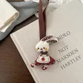 Close-up of cute white fabric rabbit keychain with red floral apron and embroidery details - Apron Rabbit Style
