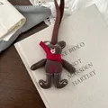 Detail of a brown fabric bear pendant with red scarf and embroidery on a vintage background - Brown Bear Style