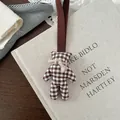 Dettaglio ravvicinato dell'orso a scacchi retrò con fiocco di iuta su libro in tessuto - Stile Orso Gingham Marrone