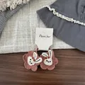 Nahaufnahme von bestickten Blumen- und Hasen-Haarspangen auf Holz mit rustikalem Design - Hellbraun Blume Hase Haargummi