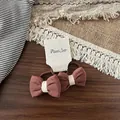 Dettaglio di fiocchi per capelli marroni in cotone su uno sfondo di legno naturale - Elastico per capelli / Scrunchie con Fiocco