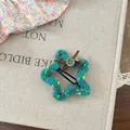 Detail of star-shaped knitted hair clip with colorful dots, button, and ribbon bow - Green
