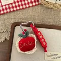 Detailansicht eines roten Plüschapfel-Anhängers mit Smile-Stickerei und Herz-Metallhaken - Apfel-Alles Läuft Gut