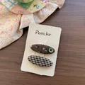 Dettaglio di fermagli per capelli in tessuto a fiori e pied-de-poule su espositore - Floreale Verde Scuro Ovale