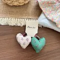 Dettaglio di elastici per capelli a cuore in tessuto floreale su carta da esposizione - Elastico per Capelli Coppia Cuore