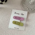 Detail of matte pastel drop hair clips in pink and green on a branded display card - Purple And Green Oval Style