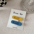 Close-up of matte waterdrop BB hair clips in blue and yellow on brand display card - Yellow And Blue Oval Style