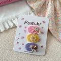 Detaillierte Makroansicht von 3er-Set Stoff-Haarspangen mit Häkelblumen und Perlen - Pink Yellow Purple