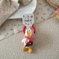 Detail van pluchen eend haar elastiekje met rode strik en bloemborduursel op zachte basis - Beige Bandana Eend Stijl