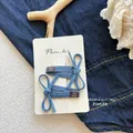 Paar tiefblaue Haarspangen aus Denim-Stoff mit Schleifendesign auf Displaykarte - Denim Schleife