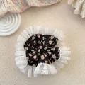 Dettaglio di un elastico per capelli floreale con pizzo su sfondo color crema - Nero Floreale