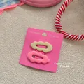Detail of wavy cloud-shaped hair clips in pastel yellow and pink colors on display card - Beige and Pink