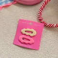 Detail of wavy cloud-shaped hair clips in pastel yellow and pink colors on display card - Beige and Pink