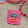 Detail view of wavy hair clips in mint green and coral orange on pink display card - Dark Green and Orange