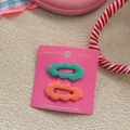 Dettaglio di fermagli per capelli ondulati verde menta e corallo su scheda rosa - Verde Scuro e Arancione
