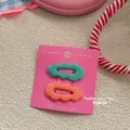 Detail view of wavy hair clips in mint green and coral orange on pink display card - Dark Green and Orange