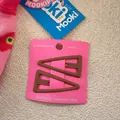 Close-up of two matte brown triangle hair clips displayed on a pink card packaging - Coffee (3)