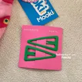 Close-up of matte dark green triangle hair clips on a pink display card - Green