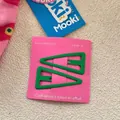 Close-up of matte dark green triangle hair clips on a pink display card - Green