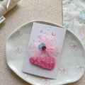 Primer plano de horquillas de lazo rosa y clips BB en cartón blanco de pantalla - Estilo de Lentejuelas con Lazo Rosa