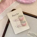 Dettaglio di fermagli per capelli a fragola ricamati a mano con perle su sfondo rosa - Stile Fragola Rosa