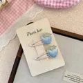 Close-up of blue strawberry embroidery hair clips with delicate pearls and pink wraps - Blue Strawberry Style