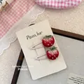 Dettaglio di due fermagli per capelli a fragola ricamati a mano con foglie e semi bianchi - Stile Fragola Rossa