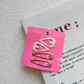 Detail van vier glitterende hart- en waterdruppelvormige haarspeldjes op roze kaart - Stijl 1: Beige Hart en Oranjebruin Waterdruppel