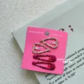 Detail van vier glitter haarspeldjes in hart- en druppelvorm op een displaykaart - Stijl 2: Roze Hart en Donkerrood Waterdruppel