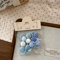 Détail de chouchous à boutons en tissu bleu avec motifs à carreaux et à rayures - Attache Pouce Haricot Carreaux Bleu