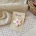 Primer plano de pinza para pelo con flor rosa y centro de cuadros sobre cartón ecológico - Pinza de Flor Rosa Pálido