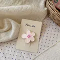 Primer plano de pinza para pelo con flor rosa y centro de cuadros sobre cartón ecológico - Pinza de Flor Rosa Pálido